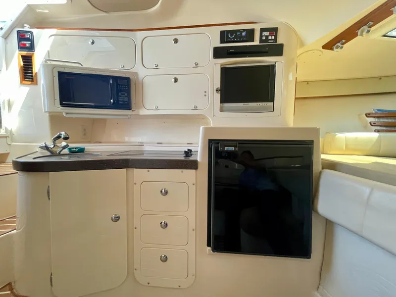 Slide: The Image of 2007 Grady-White Express 330 interior with kitchenette, featuring microwave, sink, and refrigerator. - 12