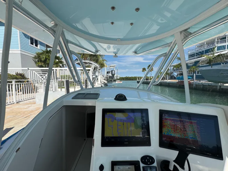 Slide: The Image of 2021 Contender 39 Fisharound boat cockpit with navigation screens, docked near waterfront homes. - 16