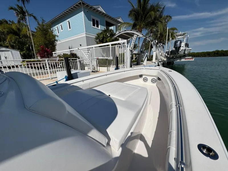 Slide: The Image of 2021 Contender 39 Fisharound boat docked by waterfront home, surrounded by palm trees. - 17
