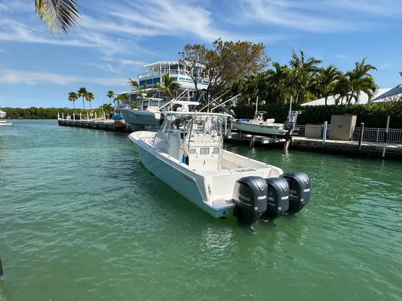 Slide: The Image of 2021 Contender 39 Fisharound boat with triple engines docked in a tropical marina. - 2