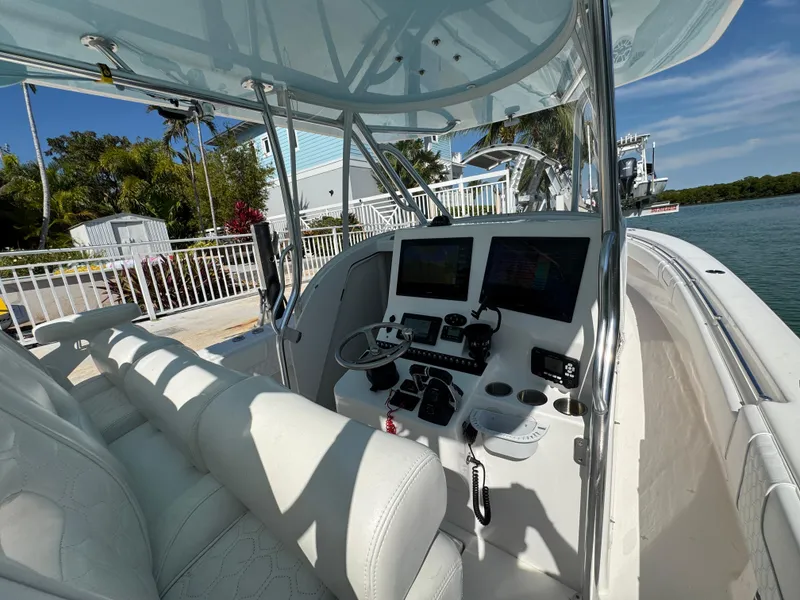 Slide: The Image of 2021 Contender 39 Fisharound boat cockpit with modern controls and seating, docked by the water. - 27