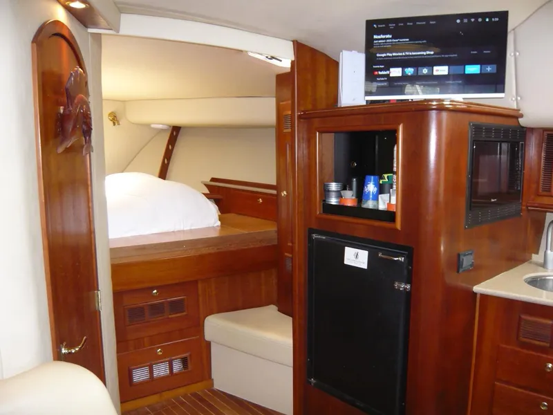 Slide: The Image of Luxurious 2004 Rampage 38 Express yacht interior with wood finish, kitchenette, and cozy sleeping area. - 11