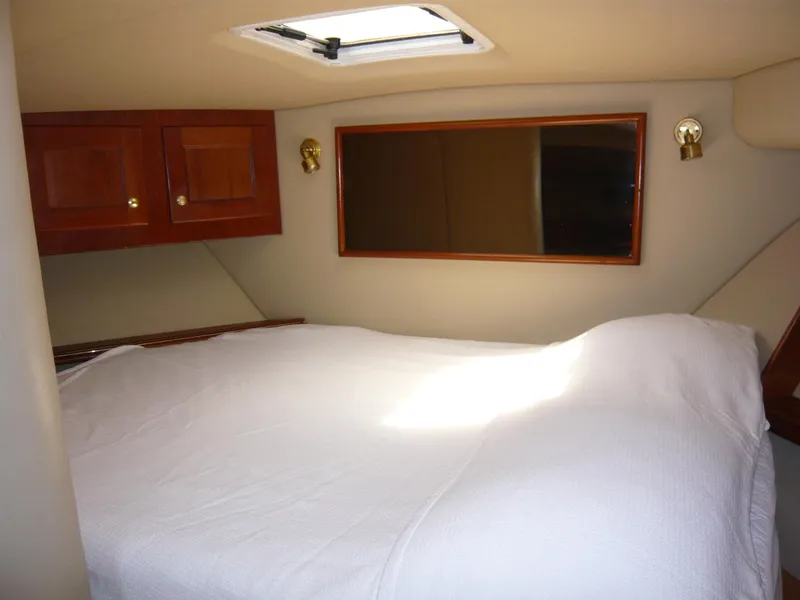 Slide: The Image of 2004 Rampage 38 Express cabin interior with bed, wooden cabinets, and skylight. - 12
