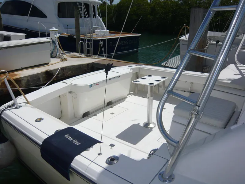 Slide: The Image of 2004 Rampage 38 Express boat docked, featuring a spacious deck and fishing rod holders. - 7