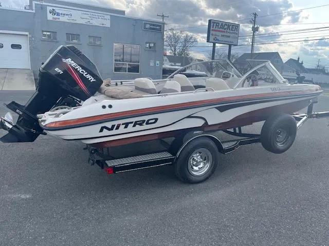 Slide: The Image of 2009 Nitro 189 Sport boat with Mercury engine on trailer, parked outdoors. - 1