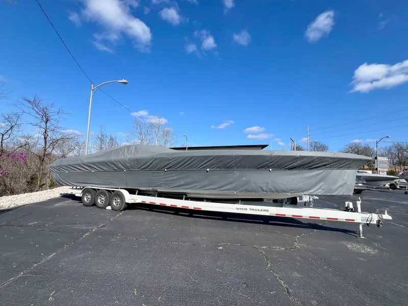Slide: The Image of 1999 Black Thunder 430 Flat Deck boat covered on trailer under blue sky. - 10