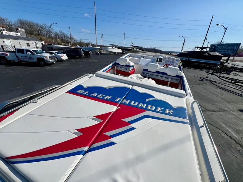 Slide: The Image of 1999 Black Thunder 430 Flat Deck boat with vibrant graphics, parked outdoors. - 11