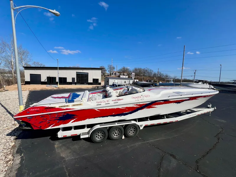 Slide: The Image of 1999 Black Thunder 430 Flat Deck boat on trailer, vibrant red and white design. - 2