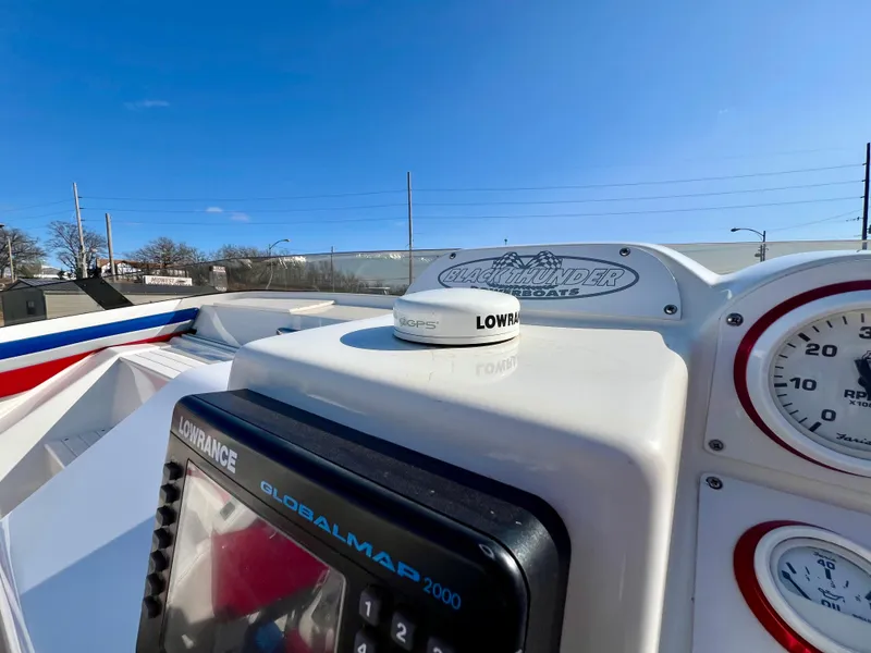 Slide: The Image of 1999 Black Thunder 430 Flat Deck boat dashboard with Lowrance GPS and gauges under clear blue sky. - 23