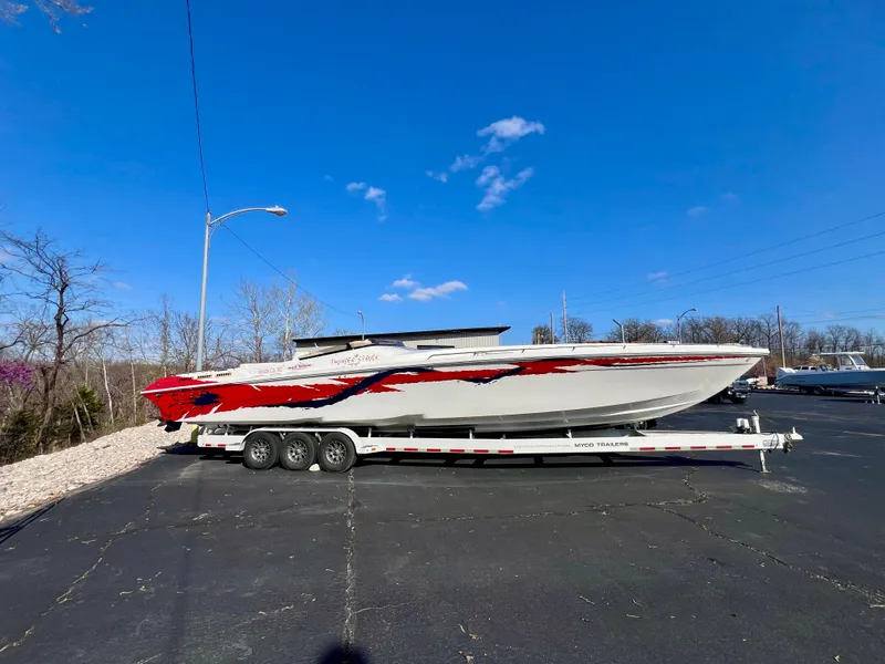 Slide: The Image of 1999 Black Thunder 430 Flat Deck boat with red and black design on a trailer. - 4