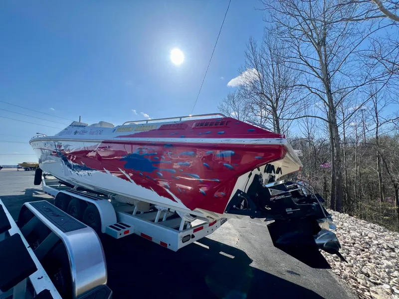 Slide: The Image of Red and white 1999 Black Thunder 430 Flat Deck boat on trailer under bright sun. - 6