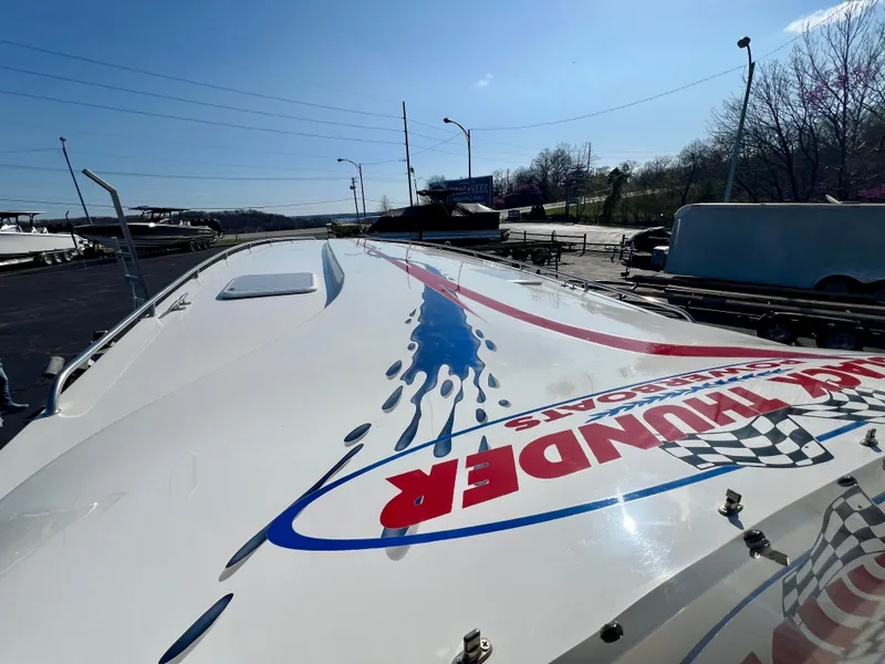 Slide: The Image of 1999 Black Thunder 430 Flat Deck boat with vibrant graphics on deck under clear blue sky. - 9