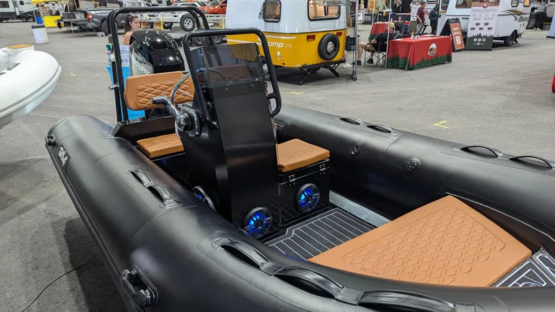 Slide: The Image of Tide Craft Custom Catalina 13 boat, 2025 model, with black exterior and tan seating, displayed indoors. - 3