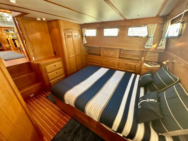 Slide: The Image of Luxurious 1997 Sabre Cockpit Motor Yacht bedroom with wood paneling and striped bedding. - 21
