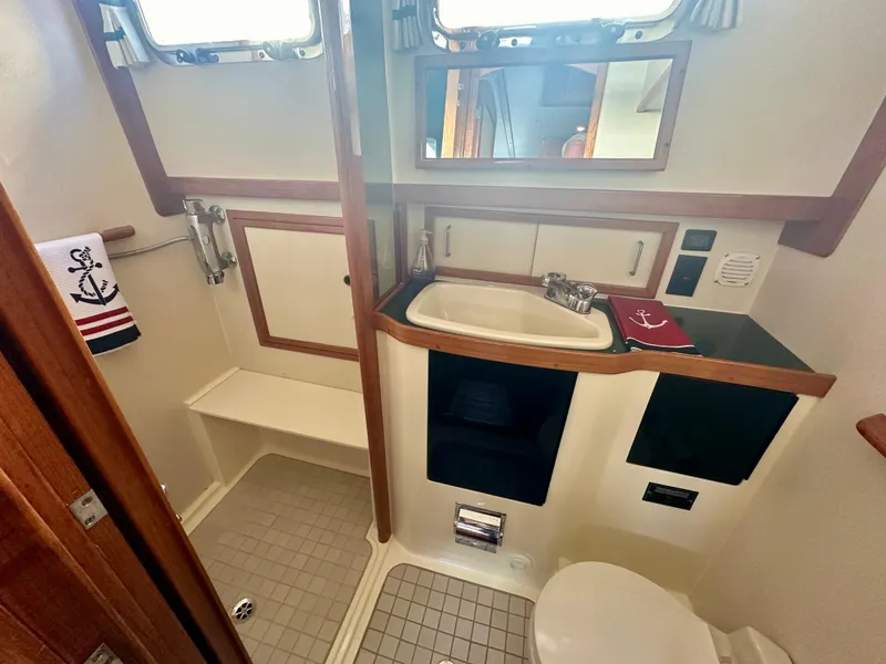 Slide: The Image of 1997 Sabre Cockpit Motor Yacht bathroom with sink, toilet, and nautical-themed decor. - 25