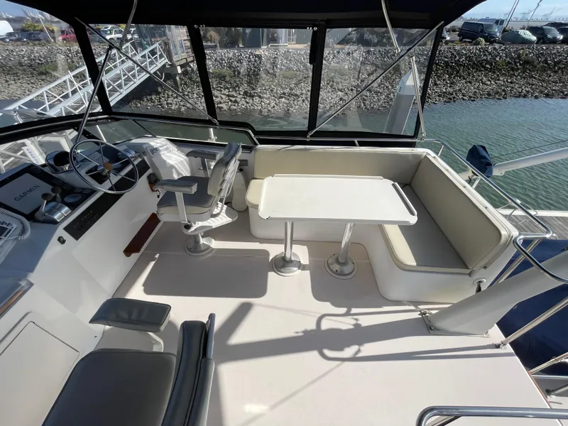 Slide: The Image of 1997 Sabre Cockpit Motor Yacht interior with helm, seating, and table, docked by the water. - 35