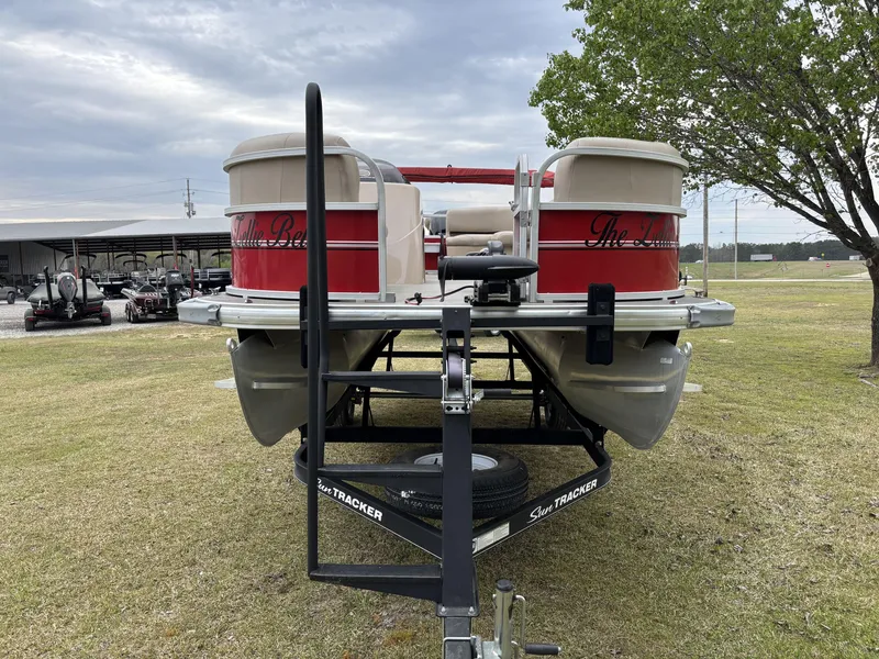 Slide: The Image of 2017 Sun Tracker Party Barge 18 DLX pontoon boat on trailer, parked on grass. - 4