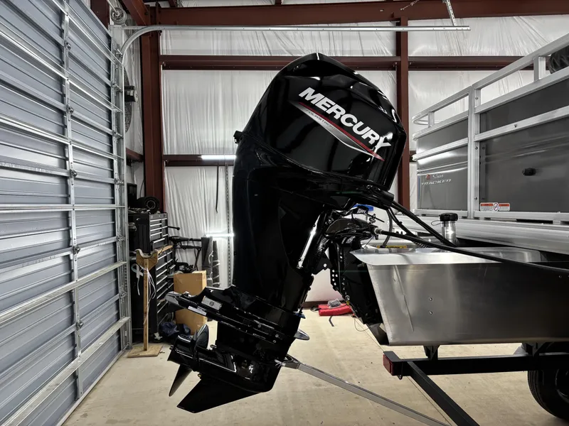 Slide: The Image of 2025 Sun Tracker Fishin Barge 20 DLX with Mercury outboard motor in a garage. - 12