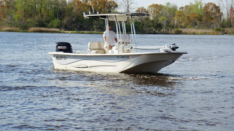 Slide: The Image of 2018 Carolina Skiff 198DLV boat cruising on a calm river with trees in the background. - 3