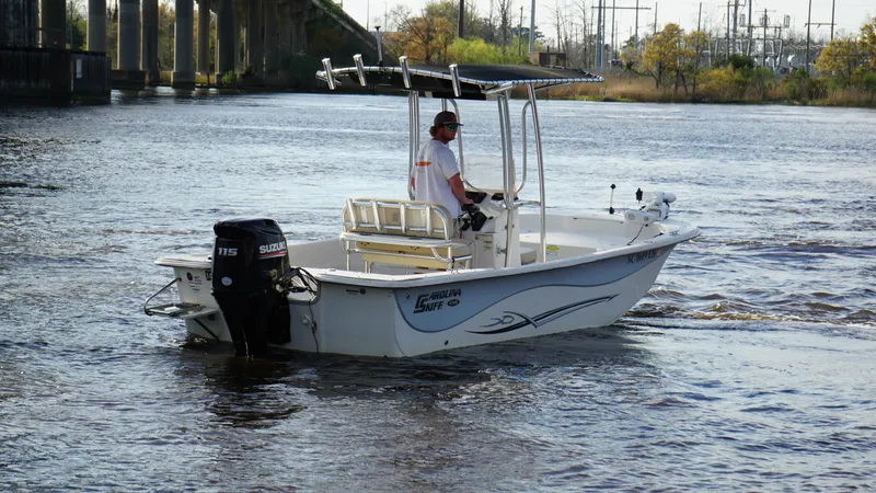 Slide: The Image of 2018 Carolina Skiff 198DLV boat cruising on a river with a bridge in the background. - 5