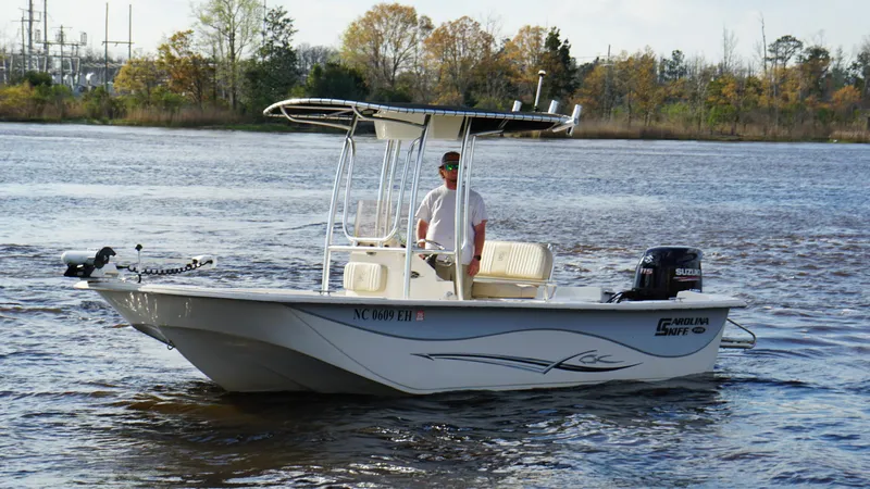 Slide: The Image of 2018 Carolina Skiff 198DLV boat on a calm lake with a person at the helm. - 7