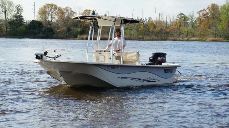 Slide: The Image of 2018 Carolina Skiff 198DLV boat cruising on a calm lake with trees in the background. - 9