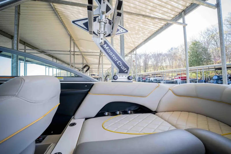 Slide: The Image of 2010 MasterCraft X25 boat interior with luxurious seating and sleek design under a covered dock. - 14