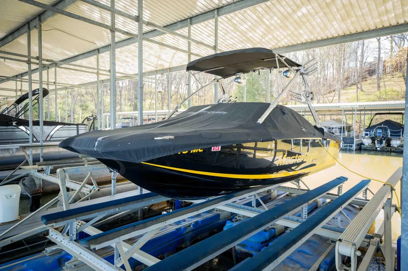 Slide: The Image of 2010 MasterCraft X25 boat in covered dock, black with yellow accents. - 7