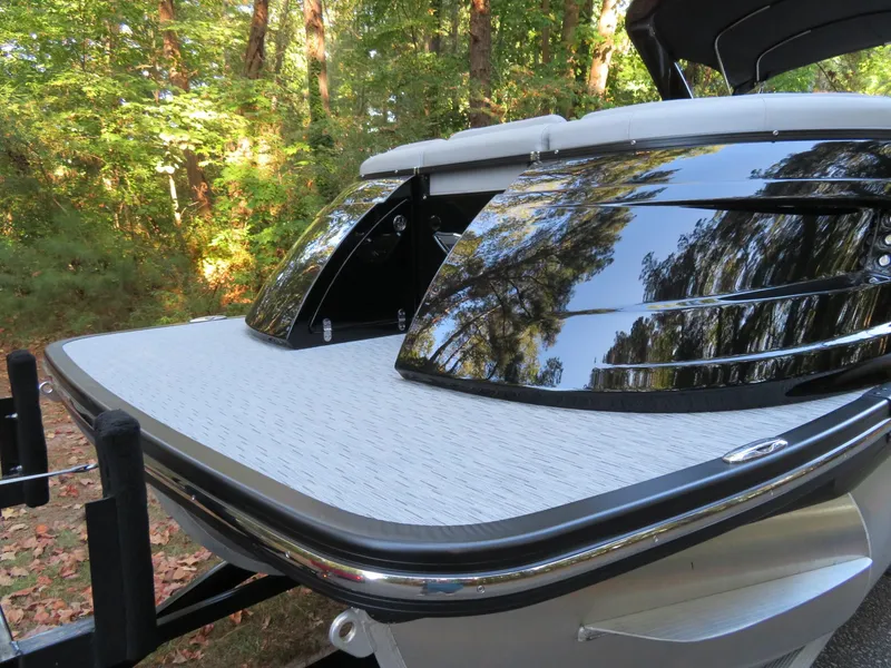 Slide: The Image of 2020 Bennington 25QXSBWAIO boat with sleek design, reflective surfaces, and forest backdrop. - 24