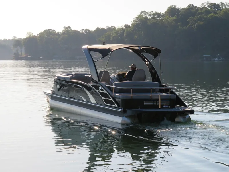 Slide: The Image of 2020 Bennington 25QXSBWAIO pontoon boat cruising on a serene lake. - 3