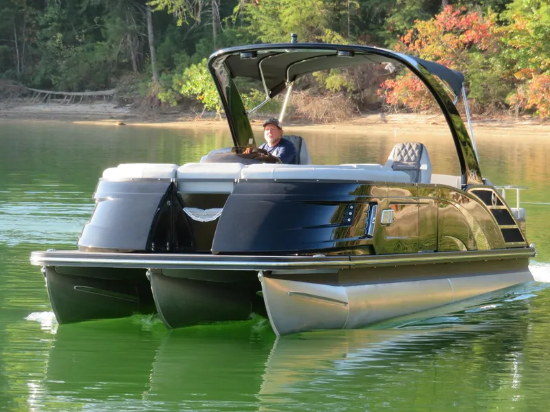 Slide: The Image of 2020 Bennington 25QXSBWAIO pontoon boat cruising on a serene lake. - 5