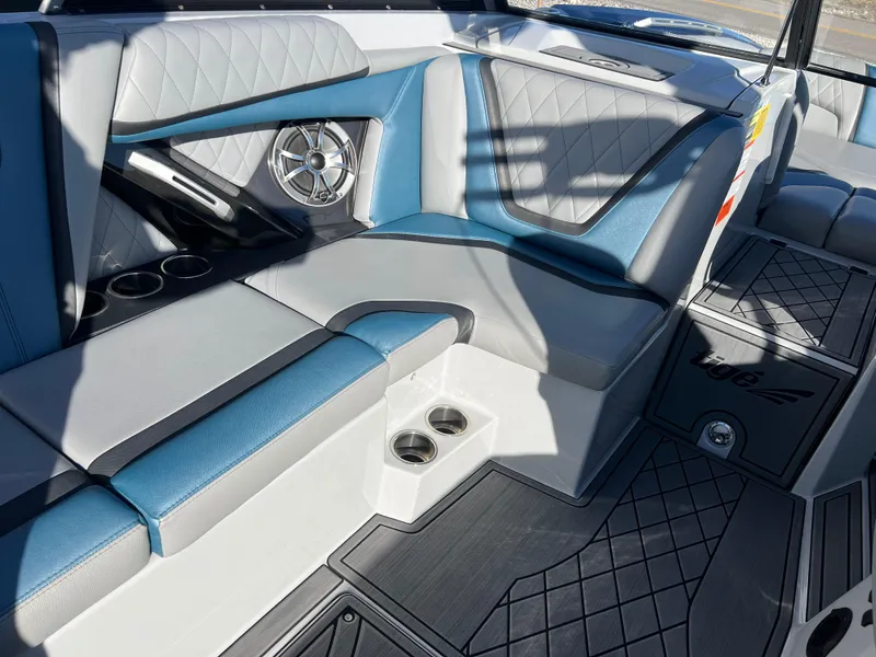 Slide: The Image of 2018 Tigé RZX3 boat interior with blue and gray seating, cup holders, and speaker system. - 15