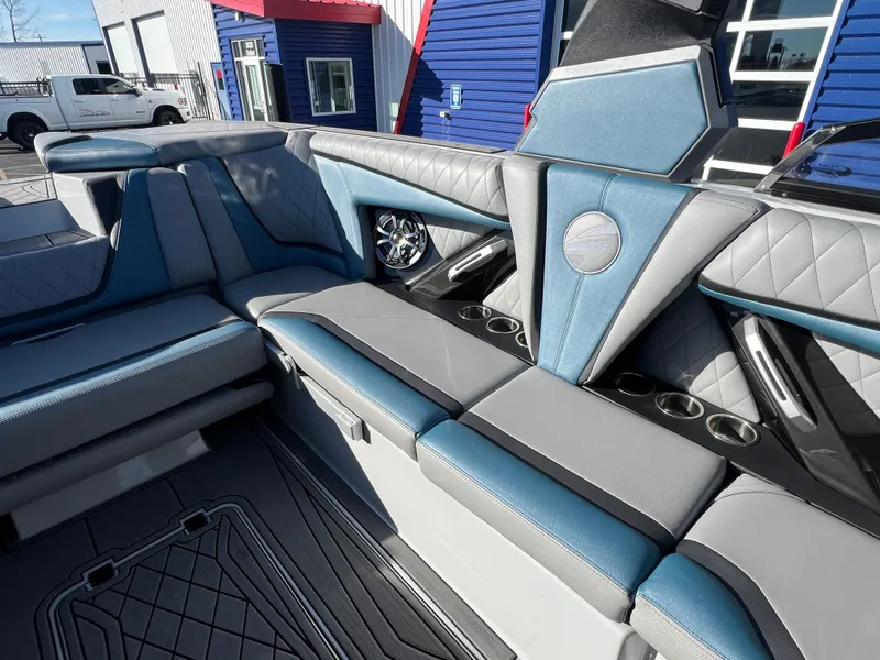 Slide: The Image of 2018 Tigé RZX3 boat interior with blue and gray seating, cup holders, and speaker system. - 16