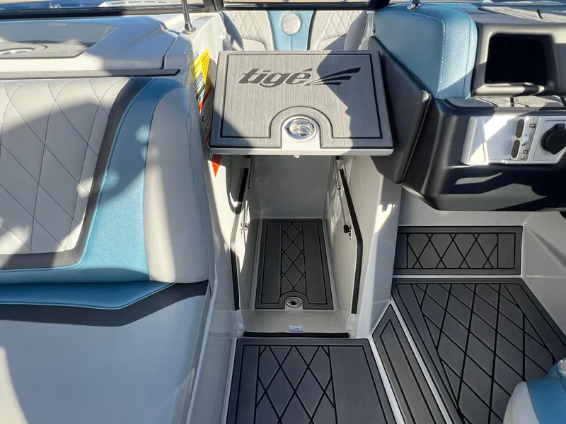 Slide: The Image of 2018 Tigé RZX3 boat interior with blue and gray seating, open storage compartment. - 20