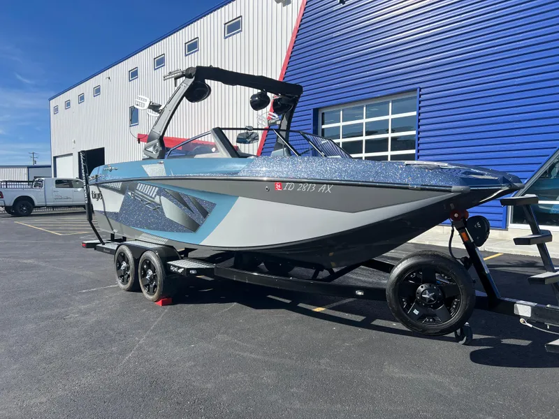 Slide: The Image of 2018 Tigé RZX3 boat on trailer, parked near blue and white building. - 4