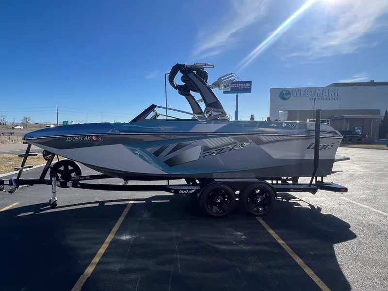 Slide: The Image of 2018 Tigé RZX3 boat on trailer in parking lot, clear blue sky background. - 9