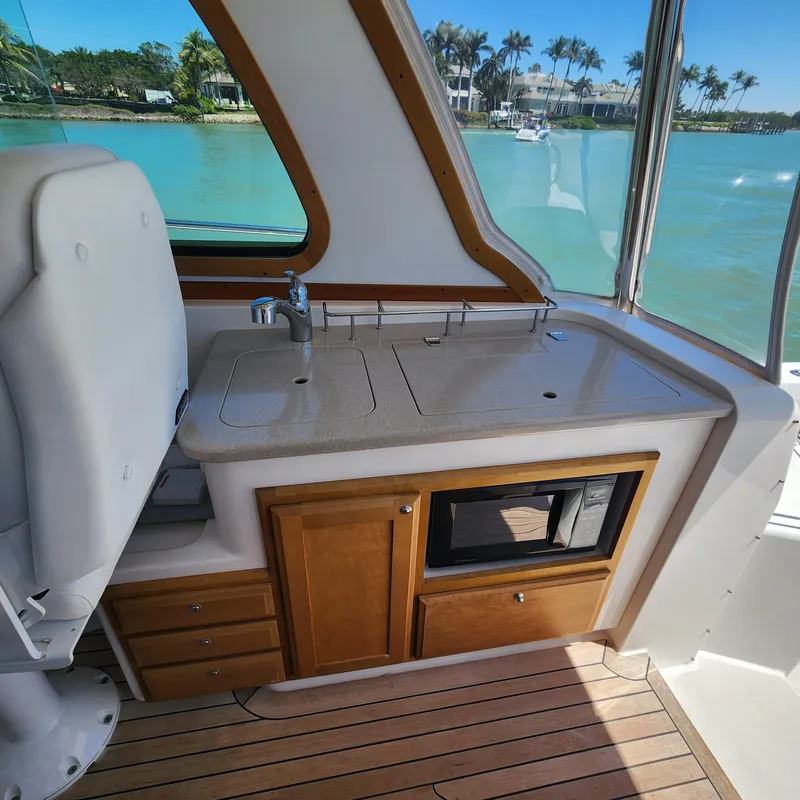 Slide: The Image of 2009 Sabre 34 Express yacht interior with kitchenette, featuring sink, microwave, and wooden cabinetry. - 31