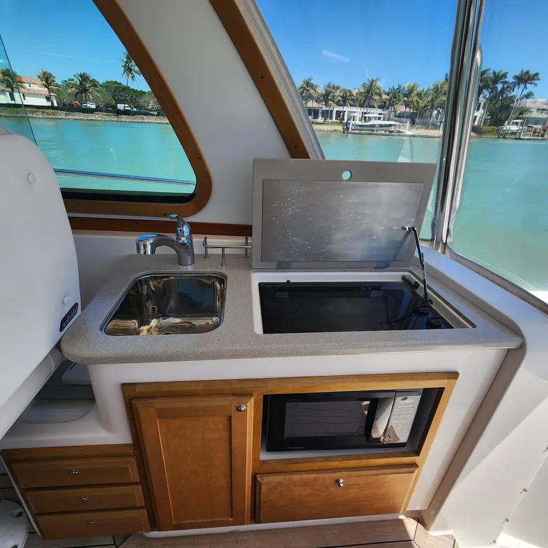Slide: The Image of 2009 Sabre 34 Express yacht kitchenette with sink, stove, and microwave, overlooking serene waters. - 32