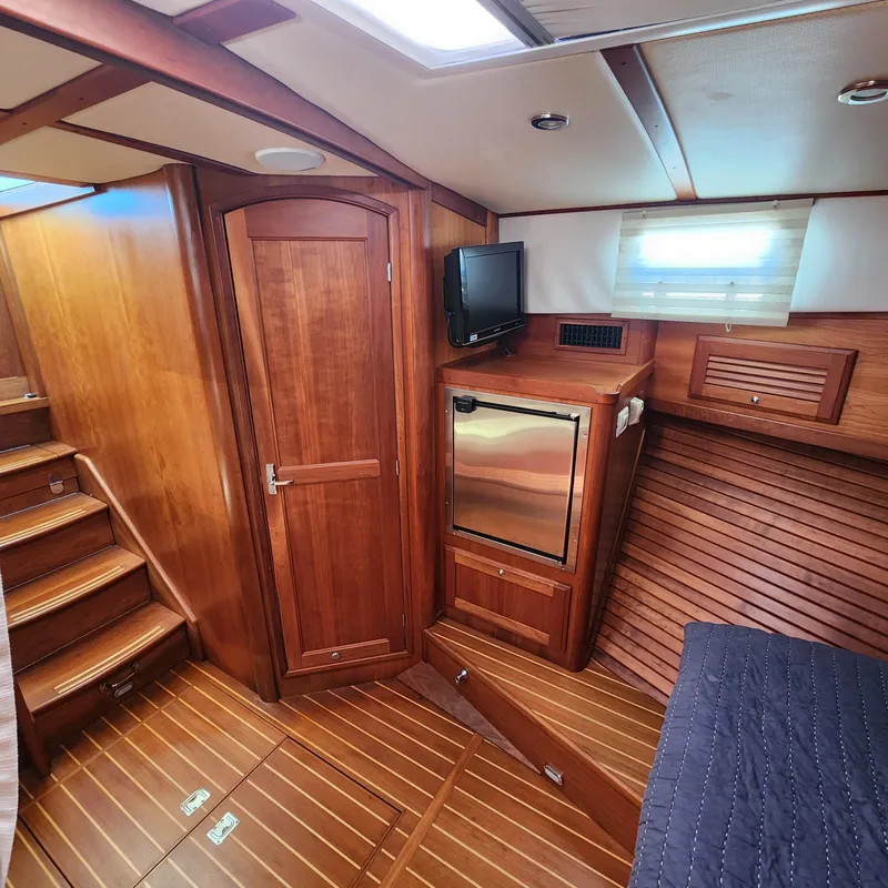 Slide: The Image of 2009 Sabre 34 Express cabin interior with wood finish, TV, and compact fridge. - 37