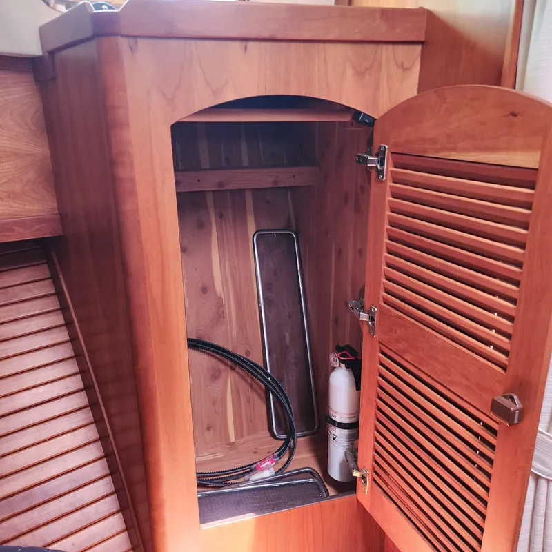 Slide: The Image of Wooden cabinet interior on 2009 Sabre 34 Express boat, featuring fire extinguisher and cables. - 41