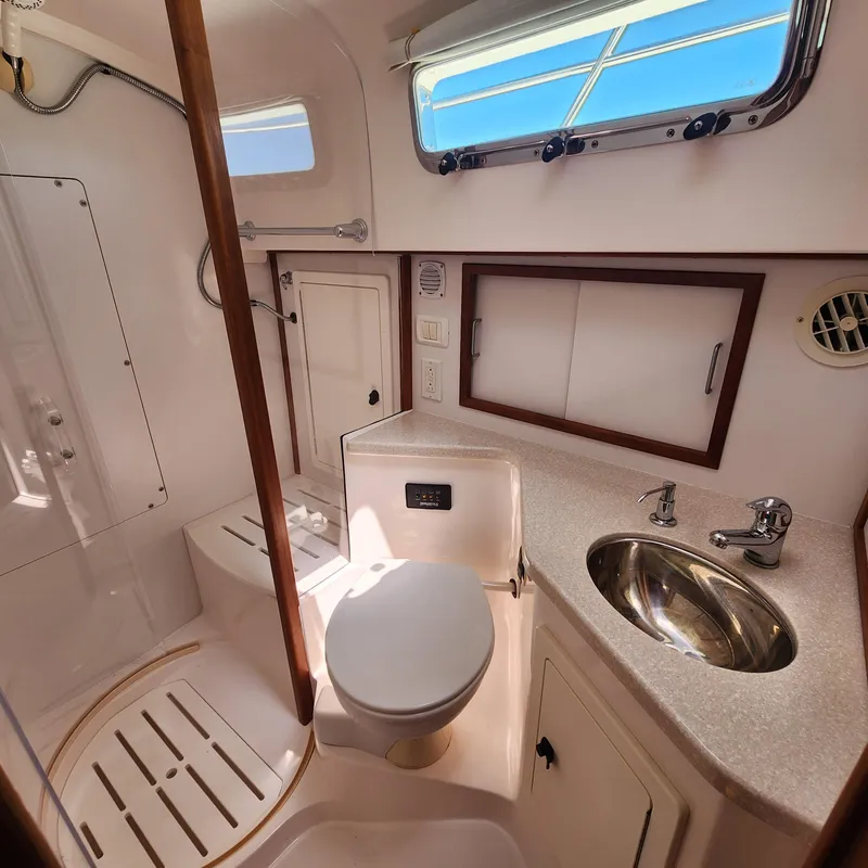 Slide: The Image of 2009 Sabre 34 Express yacht bathroom with toilet, sink, and shower, featuring natural light. - 46