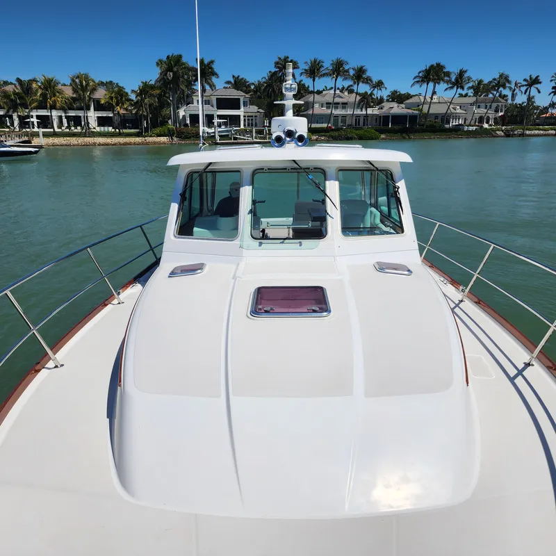 Slide: The Image of 2009 Sabre 34 Express yacht on calm water, with clear sky and waterfront homes. - 9