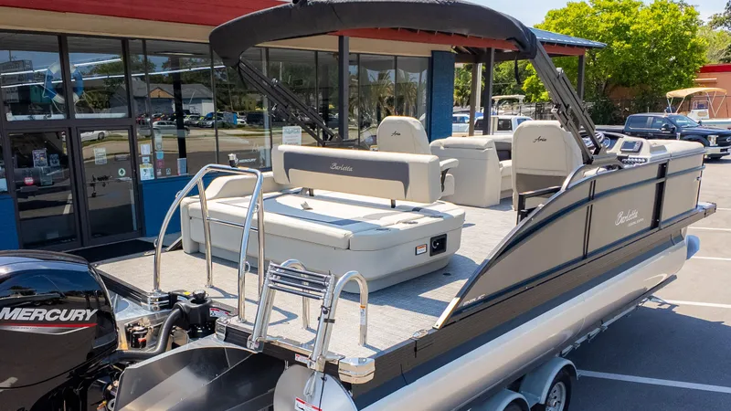 Slide: The Image of 2024 Barletta ARIA 22UC pontoon boat with Mercury engine, parked outside a dealership. - 8