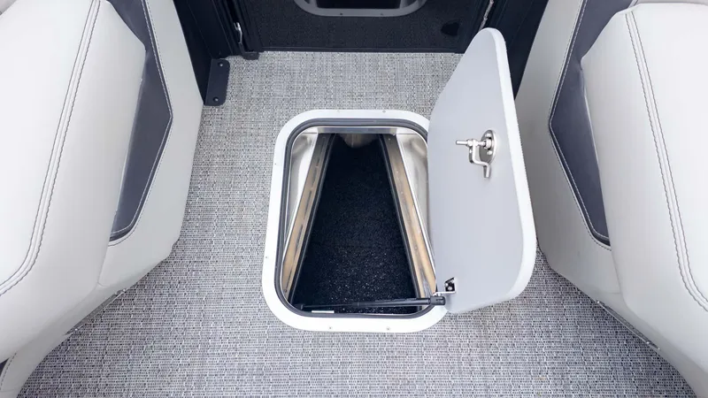 Slide: The Image of 2025 Barletta Lusso 23M boat storage compartment with open hatch on carpeted floor. - 22