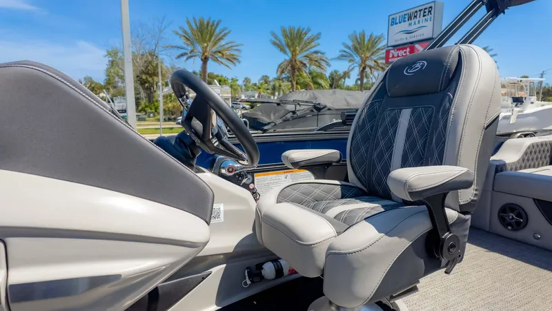 Slide: The Image of Captain's chair and helm of 2025 Barletta Lusso 25UE boat, with palm trees in background. - 25