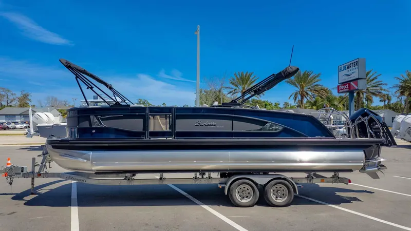 Slide: The Image of 2025 Barletta Lusso 25UE pontoon boat on trailer, parked in marina lot. - 4