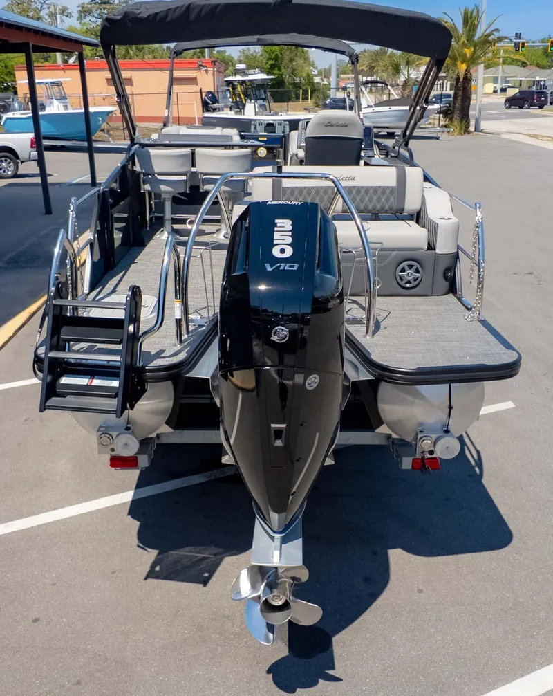 Slide: The Image of 2025 Barletta Lusso 25UE pontoon boat with powerful outboard motor, parked in a sunny lot. - 6