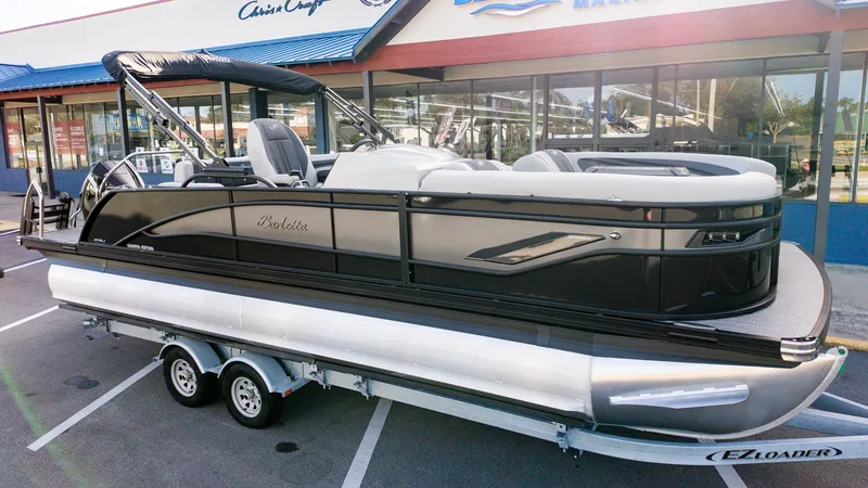 Slide: The Image of 2025 Barletta Corsa 23U pontoon boat on trailer outside dealership. - 2