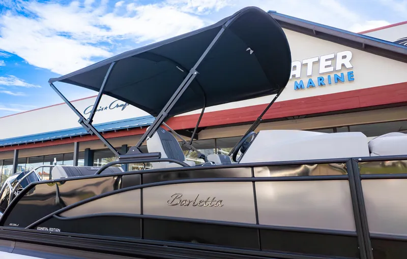 Slide: The Image of 2025 Barletta Corsa 23U boat with canopy at a marine dealership. - 24