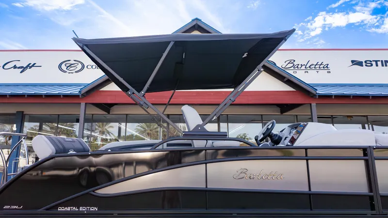 Slide: The Image of 2025 Barletta Corsa 23U boat with canopy at dealership, sunny day. - 25